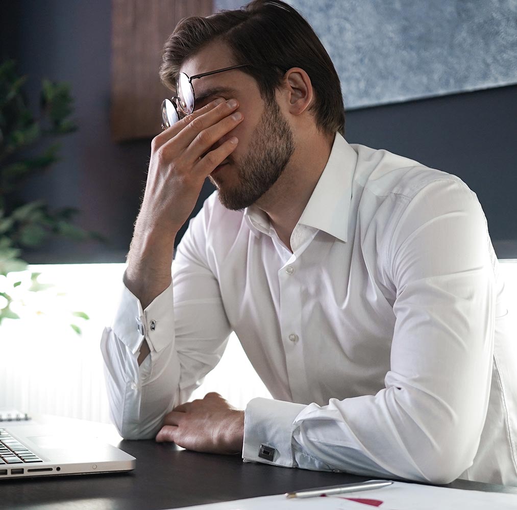 Man rubbing his tired, irritated eyes at his desk