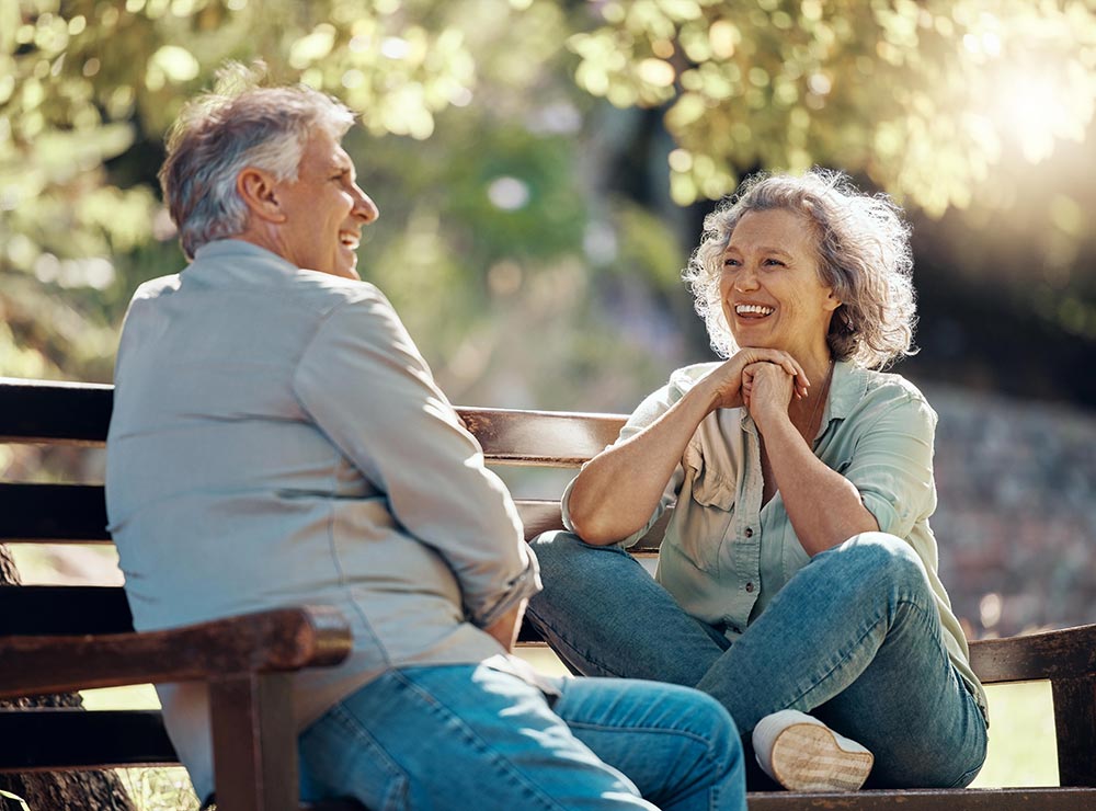 Older couple laughing together on a park bench
